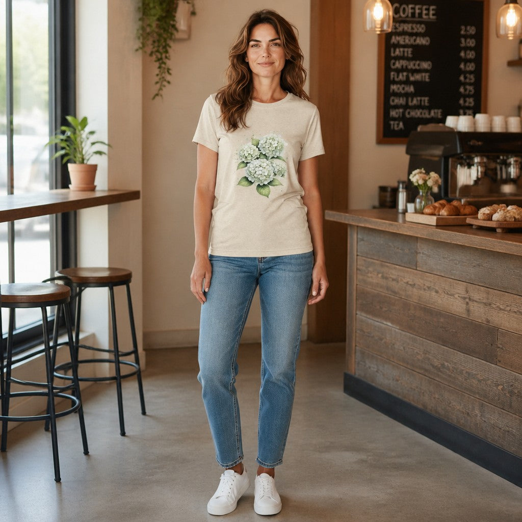 Woman wearing an Opensky Goods white tri-blend t-shirt with a watercolor hydrangea floral print in a coffee shop.